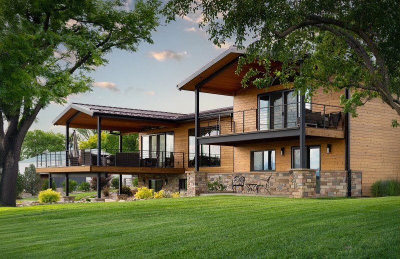 Modern farmhouse-style home remodel in Boulder, Colorado featuring custom wood siding, elevated steel-supported decks, and expansive glass doors—expertly designed and built by a leading Boulder home builder specializing in custom home construction, exterior renovations, and upscale remodels tailored to Colorado’s landscape.