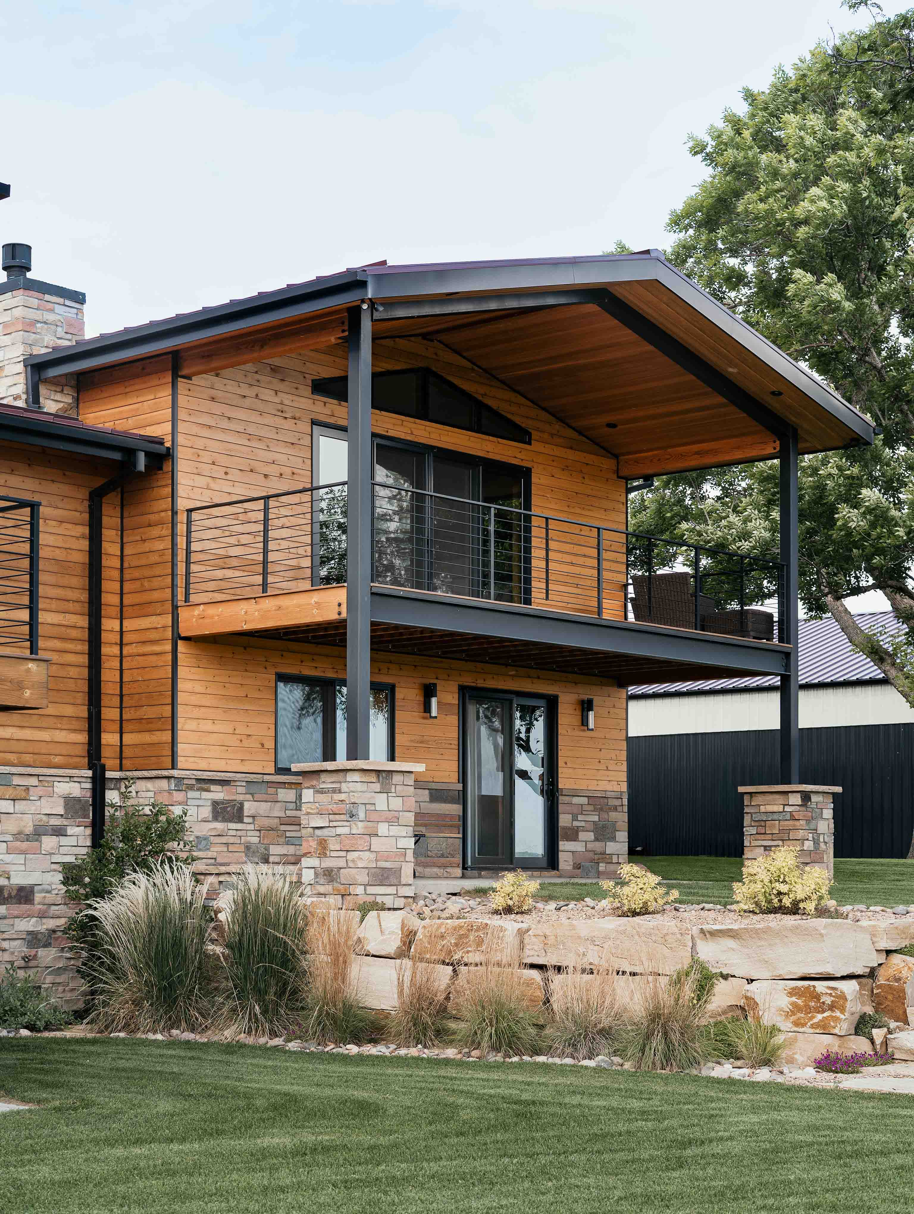 Modern custom-built home in Boulder, Colorado, featuring natural wood siding, stone accents, and a covered balcony—expertly crafted by a Boulder construction company specializing in high-end residential builds. Colorado Choice Builders