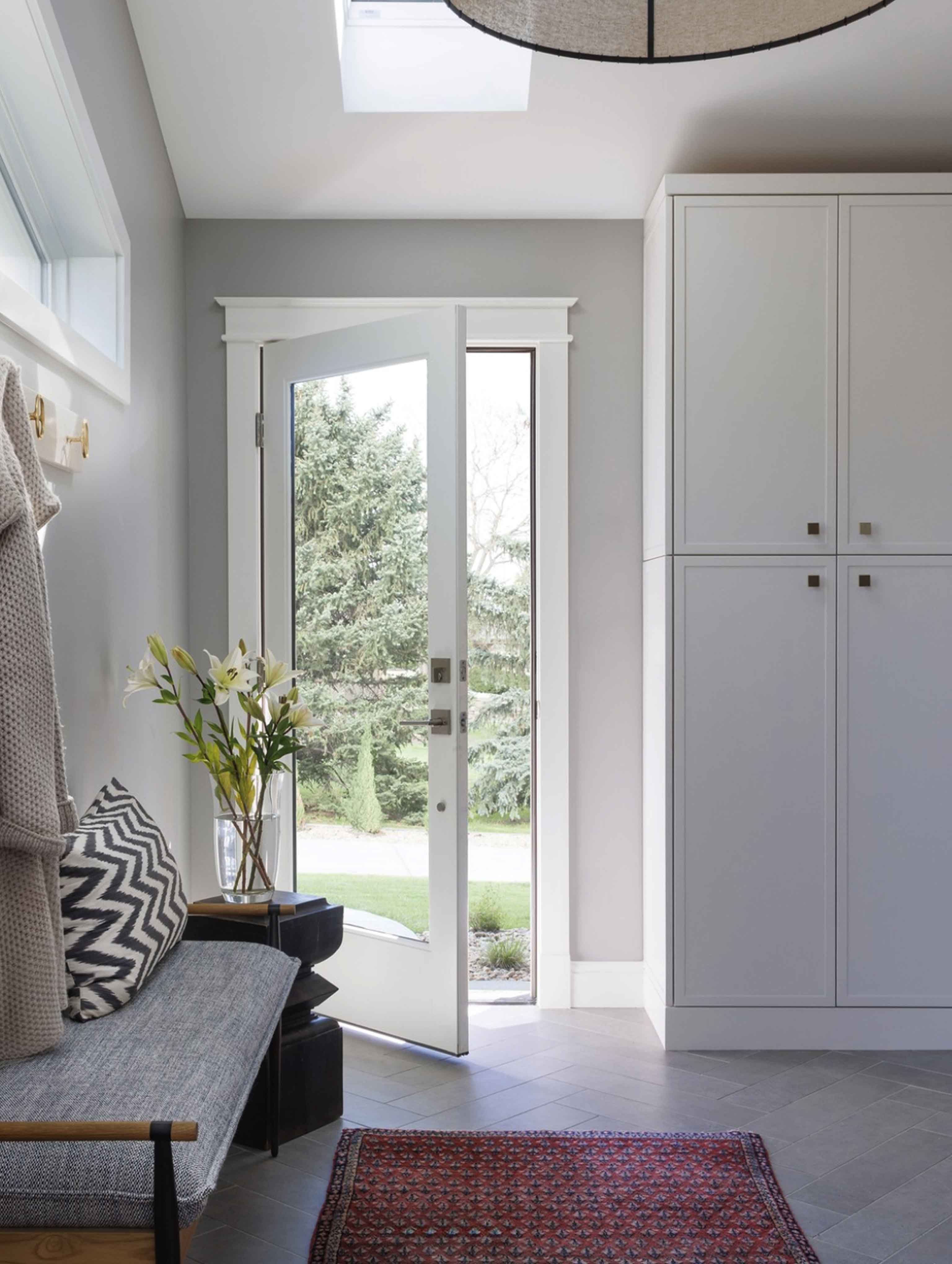 Bright and modern entryway remodel in a Boulder, Colorado home, featuring custom cabinetry, skylight, chevron-patterned pillows, and built-in storage—designed by a local home remodeling contractor specializing in functional and stylish interiors. Colorado Choice Builders